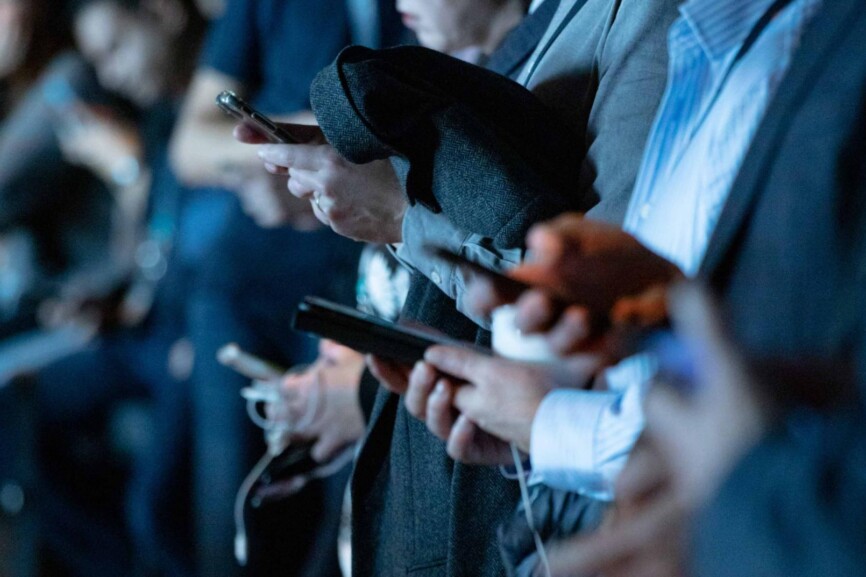 Menschen in einer Reihe schauen auf ihre Smartphones.