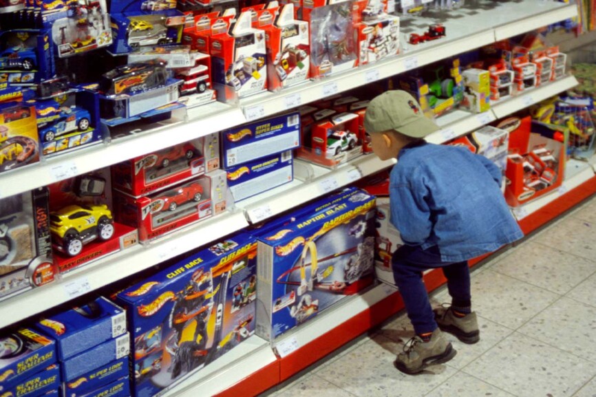 Kind steht vor einem Regal mit Spielwaren