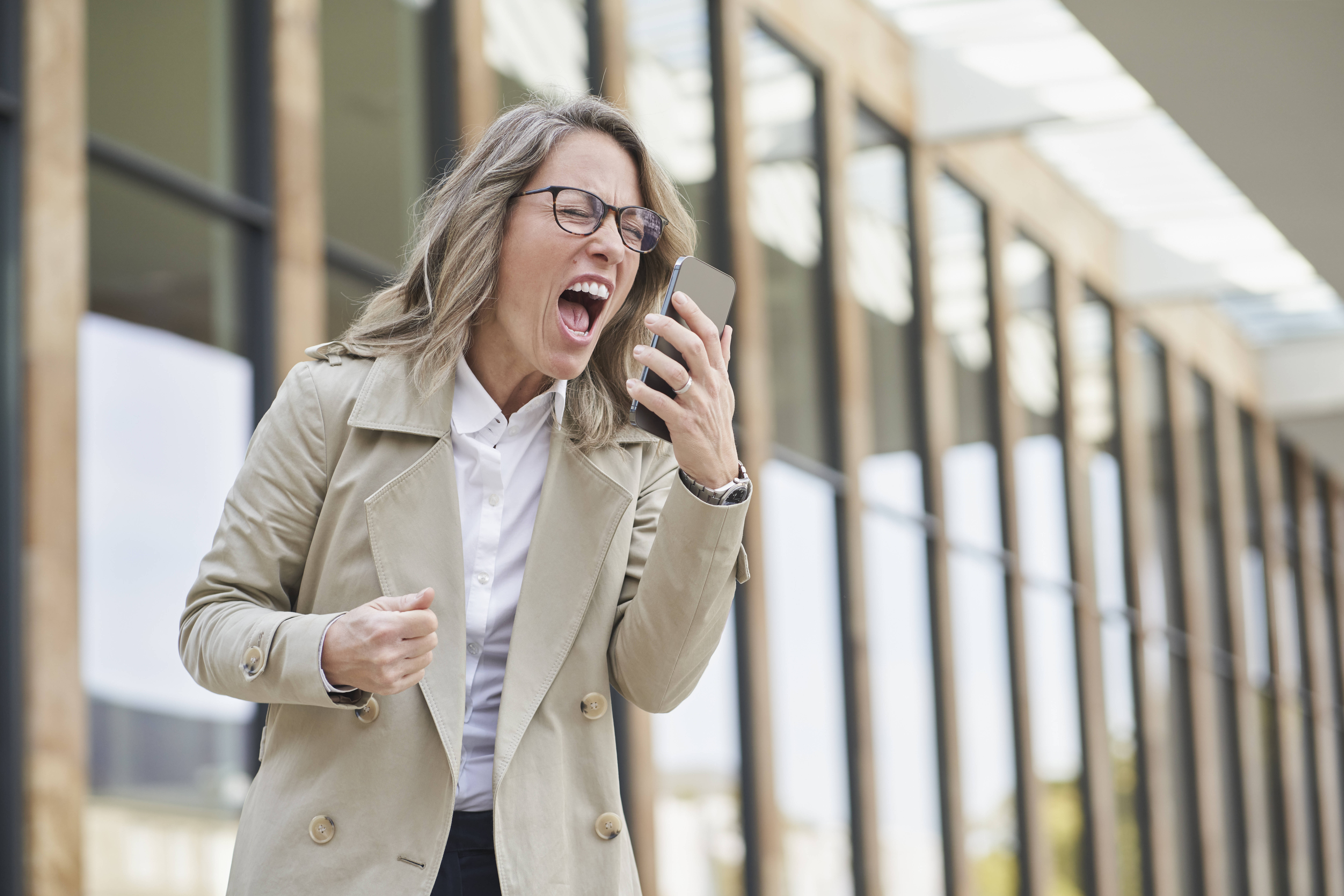 Mature businesswoman shouting on speaker phone outside building model released, Symbolfoto, RORF03320