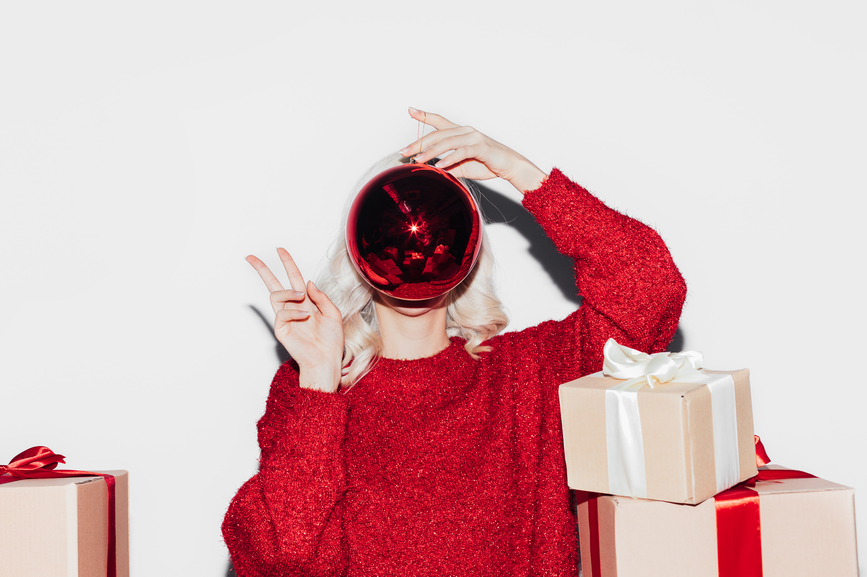 Portrait of a beautiful blond girl surrounded with lots of christmas presents in front of a white background