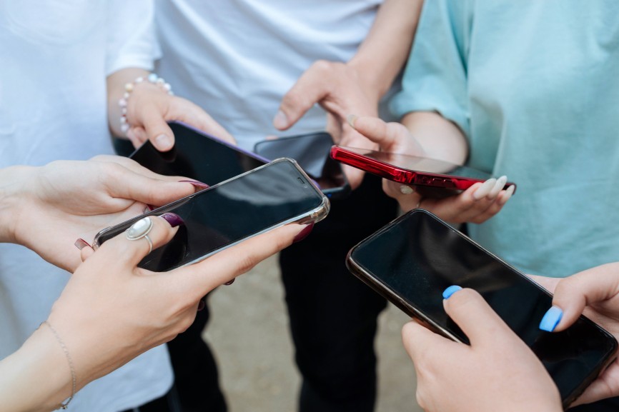 Hands of teens holding smartphones outdoors