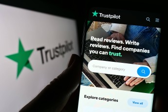 Person holding cellphone with webpage of review platform company Trustpilot Group plc on screen. Stuttgart, Germany – 01
