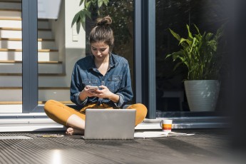 Woman sitting on terrace using cell phone and laptop for remote work model released, Symbolfoto property released, UUF34261