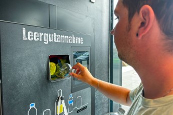 Bavaria, Germany August 16, 2025: A man returns an empty plastic bottle to a bottle return machine a symbol of recycling