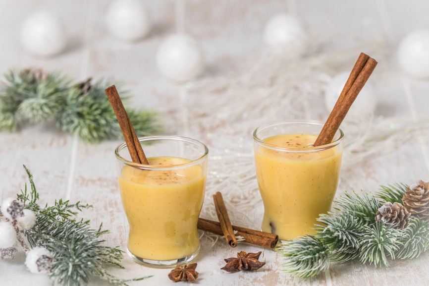 Two glasses of eggnogg with cinnamon sticks on white wooden background, christmas. Auld Man's milk, Coquito or Creme de Vie or Eierlikoer.